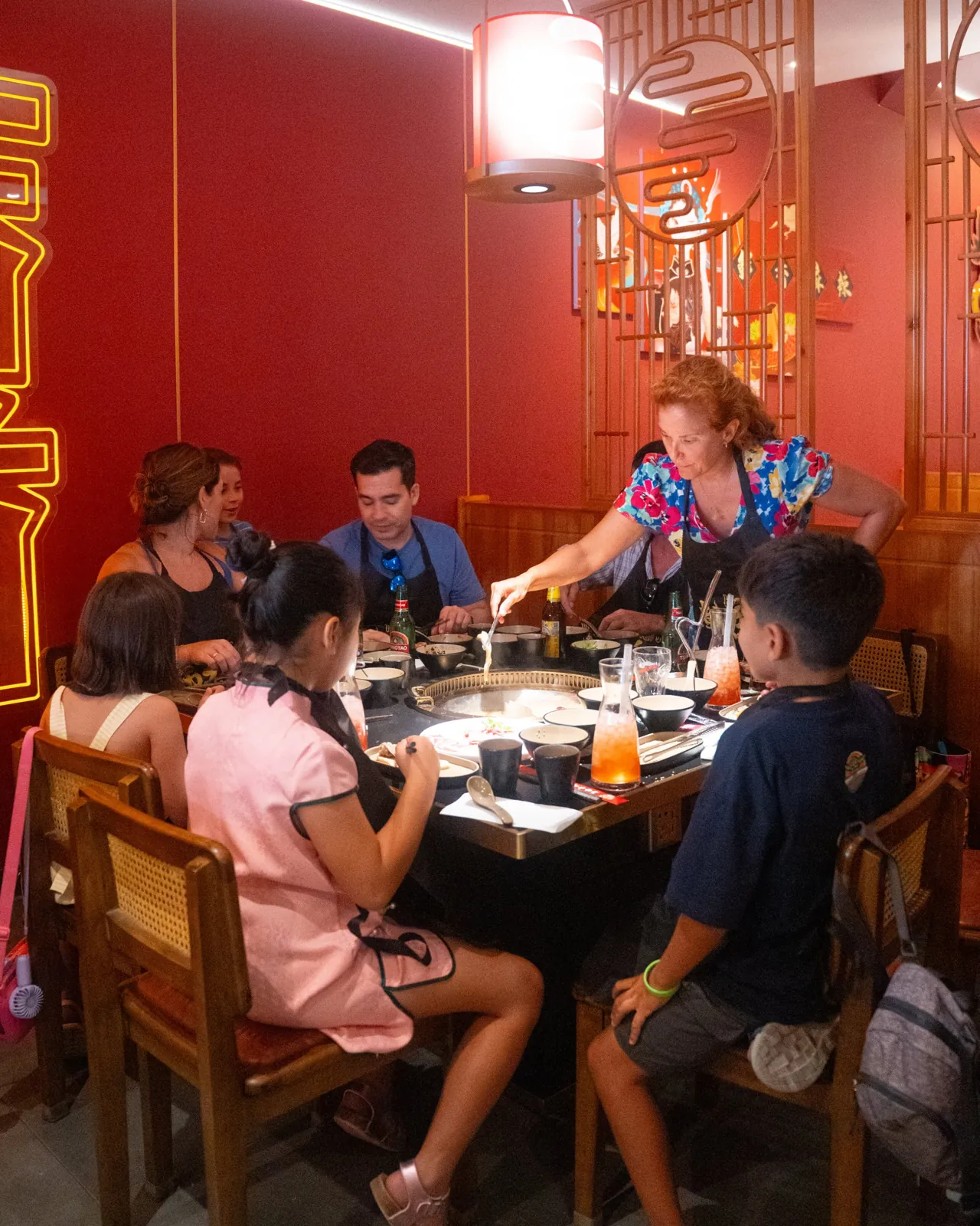 Un grupo cocina en la mesa de Liu’s Hotpot Palma mientras una camarera sirve la olla